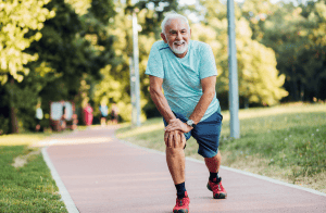 Senior man outside stretching legs on jogging path 